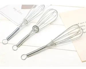 Gros plan détail du fouet en acier inoxydable avec manche à ressort pour la cuisine.
