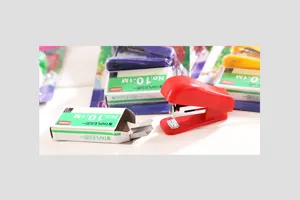 Vue détaillée du mini agrafeuse rouge et des agrafes, produit de papeterie compact.