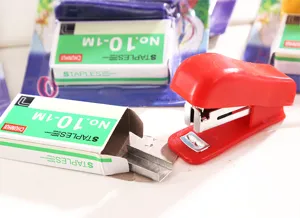 Mini agrafeuse et agrafes détail montrant le corps en plastique rouge et les agrafes.