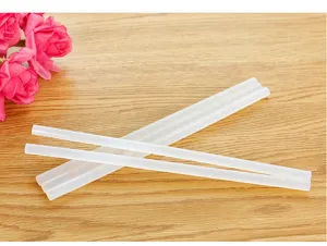 Gros plan détaillé de bâtons de colle thermofusible transparente sur fond en bois.