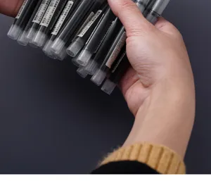 Close-up detail shot of a bunch of black quick-drying direct liquid rollerball pens held in hand.