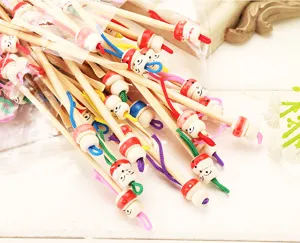 Handmade natural bamboo ear picks with cute wooden doll heads and colorful cords, detail view.