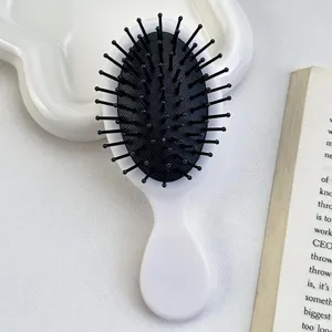 Mini portable cushion hair massage brush detail, compact design with black pins.