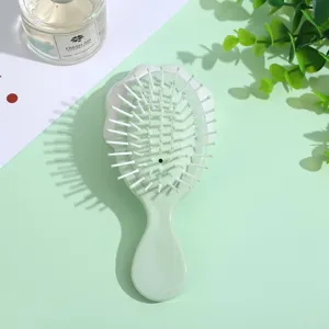 Portable green hair brush with soft white bristles and massage air cushion design for daily hair care.
