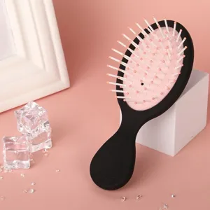 Detailed shot of a portable black handle hair massage cushion comb with pink airbag design.