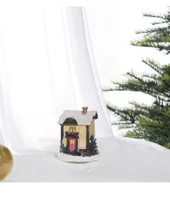 Detailed view of miniature resin Christmas house ornament with snow-covered roof detail