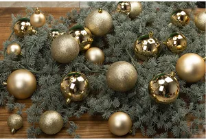 Close-up of golden Christmas balls with glossy and matte textures on green garland