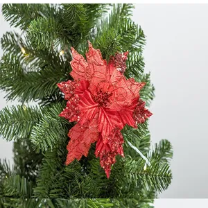 Detailed view of a red sequined poinsettia flower ornament on a green Christmas tree.