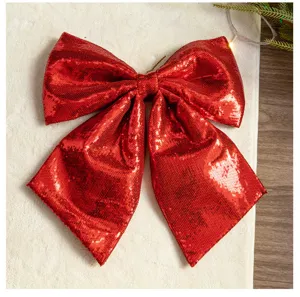 Macro view of a large red sequined Christmas bow decoration with festive lights.