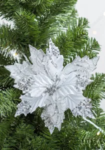 Detailed view of white artificial Christmas flower with silver sequins on green tree.