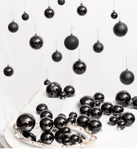 Detailed view of assorted black Christmas ornaments in matte, glossy, and glitter finishes