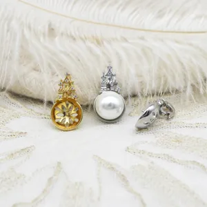 Macro detail of castle-shaped pearl setting pendants in gold and silver plating.