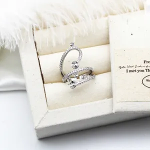 Elegantes Detail eines silbernen geometrischen Rings mit Zirkonia und Perlenfassung.