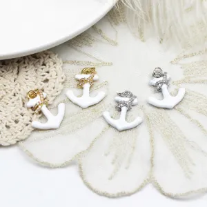 Detailweergave van witte emaille ankerbedeltjes met kristallen in goud en zilver