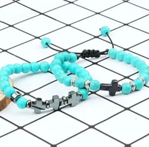Gedetailleerd overzicht van turkoois bewerkte kralenarmbanden met kruishangers en verstelbaar koord.