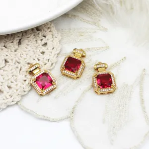 Close-up of three red zircon perfume bottle pendants in 18K gold plated copper