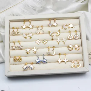 Collezione di orecchini a stella e luna con conchiglia bianca in un vassoio