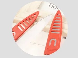 Detail shot of stainless steel fruit knife with breathable red protective sheath for kitchen use.