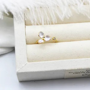 Detailed close-up of a white enamel flower ring with gold plated adjustable band