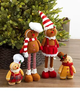 Set of four plush gingerbread dolls standing in front of a lighted Christmas tree