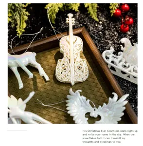 Detailed view of iridescent white Christmas ornaments featuring a violin and reindeer on a tray