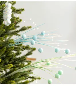 Close-up of sparkling Christmas tree sprigs with blue pom-poms and a candy ornament