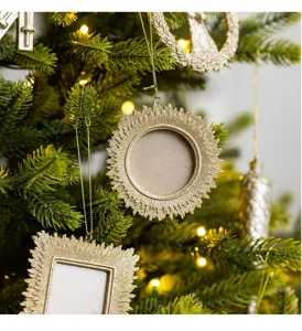 Detailaufnahme von hängenden champagnerfarbenen Harz-Fotorahmen am Weihnachtsbaum.