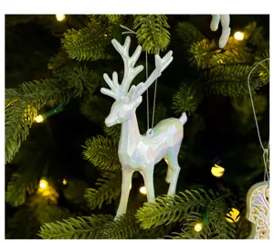 Iridescent white reindeer ornament hanging on green Christmas tree with warm lights