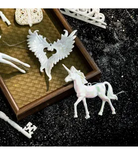 Close-up of iridescent white unicorn and angel wing Christmas tree hanging ornaments