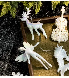 Close-up of iridescent white Christmas ornaments like reindeer and angel on a tray
