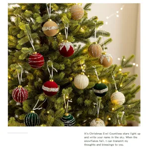 Detailed view of elegant flocked Christmas balls with glitter hanging on a lighted tree