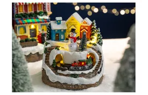 Detailed view of a lighted Christmas snow house village featuring a rotating train and snowman
