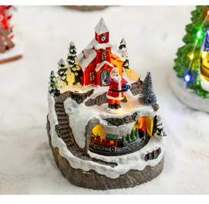 Close-up view of a glowing Christmas snow house music box with a rotating mini train.