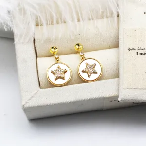 Dettaglio ravvicinato di orecchini a stella con conchiglia bianca e zircone in oro 18K