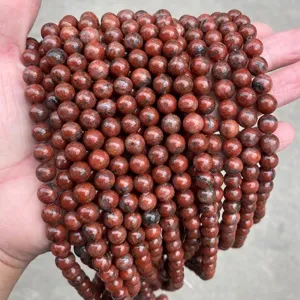 Primer plano detallado de cuentas redondas de piedra sésamo rojo natural para joyería DIY.