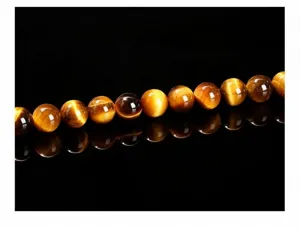 Gros plan macro de perles d'œil de tigre jaune naturel sur surface noire réfléchissante