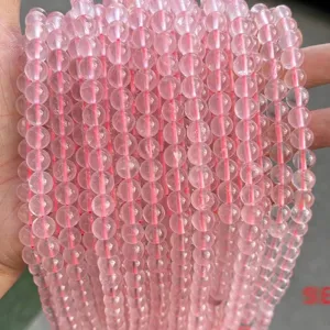 Macro detail of natural 8mm rose quartz beads with icy translucent texture and pink hue.