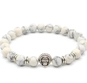 Close-up detail of white turquoise beaded bracelet with vintage silver chief charm.
