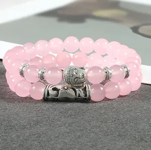 Gedetailleerde close-up van de roze kraalarmband set met Boeddha-hoofd en zonne-hanger.