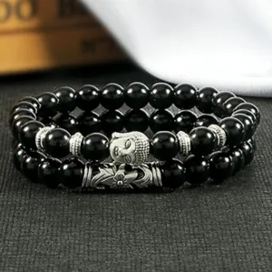 Close-up detailopname van dubbele zwarte kralen armbanden met zilveren Boeddha bedel.
