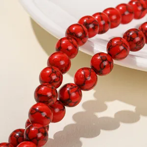 Vibrant red turquoise round beads with black spiderweb patterns for DIY jewelry.