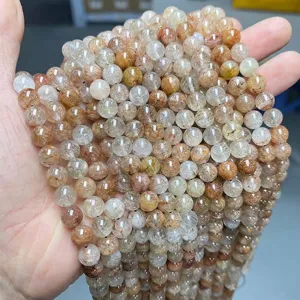 Close-up of natural red rutilated quartz round beads held in hand for DIY jewelry.
