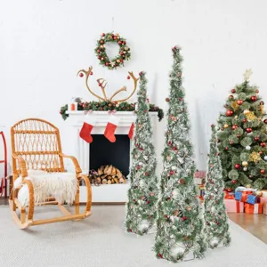 Nahaufnahme von drei schneebedeckten Weihnachts-Zapfenbäumen mit roten Beeren in Wohnambiente