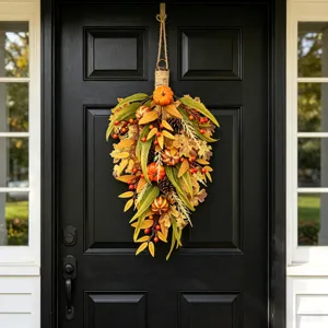 Vista detallada de corona de otoño en forma de lágrima con calabazas y bayas en puerta
