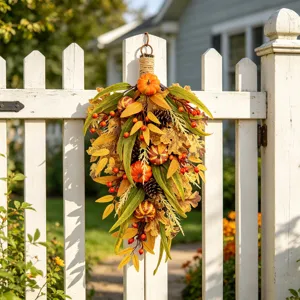 Guirnalda de otoño artificial con calabazas y bayas colgando en una valla blanca