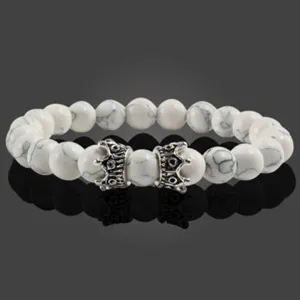 Gros plan sur le bracelet de perles en pierre blanche avec breloques couronne argent.
