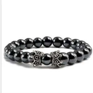Gros plan détaillé du bracelet de perles noires avec de charmantes couronnes métalliques.