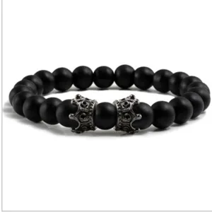 Vue rapprochée détaillée du bracelet en perles mates noires avec charmes couronne argent.