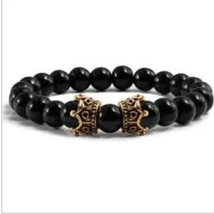 Gros plan detail de bracelet perles de pierres precieuses noires avec breloques couronne or.