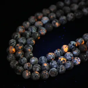 Macro view of natural Yooperlite beads showing orange UV fluorescence spots